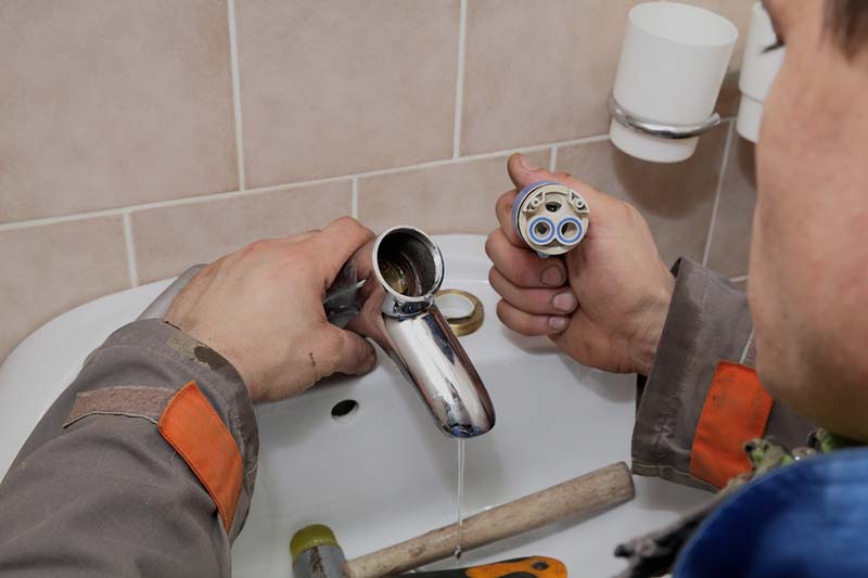 Plumber-fixing-leaking-faucet