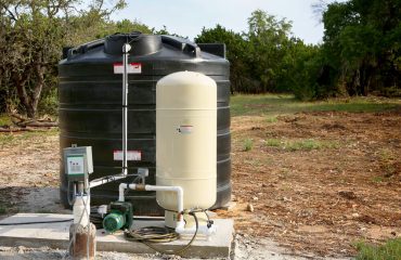 Deep water well set up, country side construction. Drilled draw well with pressure switch and storage tank.