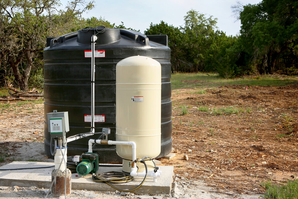 Deep water well set up, country side construction. Drilled draw well with pressure switch and storage tank.