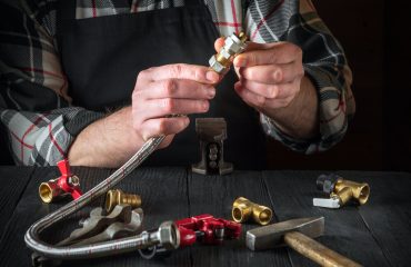 Plumber connects brass fittings to plumbing hose