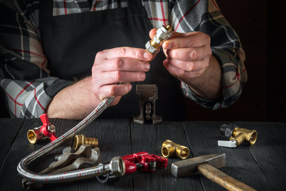 Plumber connects brass fittings to plumbing hose