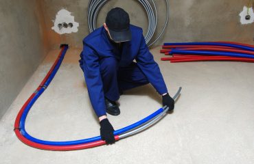 Plumber installing plastic pex pipes, doing maintenance jobs for water and heating systems.