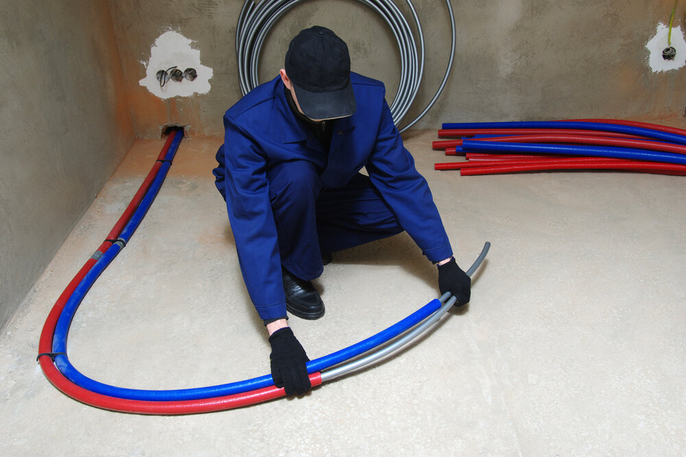 Plumber installing plastic pex pipes, doing maintenance jobs for water and heating systems.