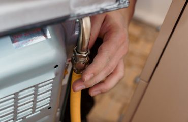 Professional Technician Connecting Gas Line to Oven for Installation.
