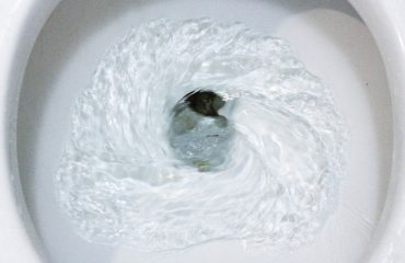 white ceramic toilet bowl in the process of flushing
