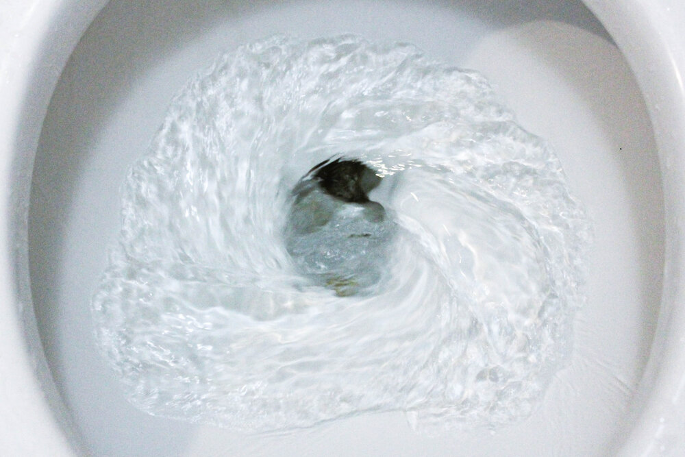 white ceramic toilet bowl in the process of flushing